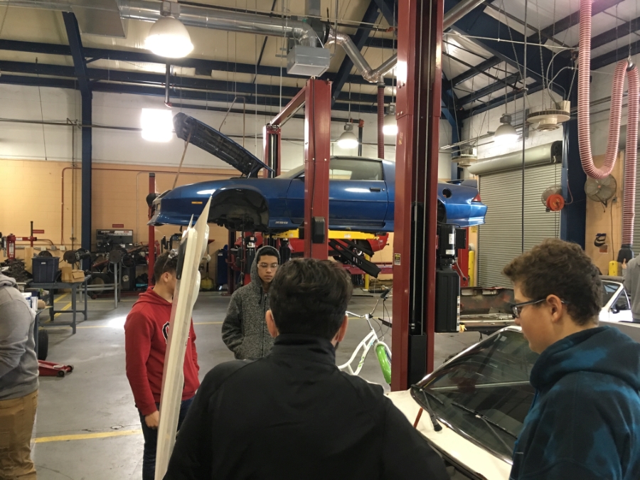 Students work on a car in the garage.